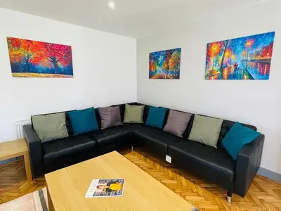 a living room with a black couch and three paintings at Warren Lodge in Little Baddow
