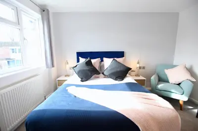 a bedroom with a blue bed and a blue chair at Stylish Cambridge City Pad in Chesterton