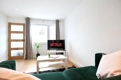 a living room with a green couch and a tv at Stylish Cambridge City Pad in Chesterton