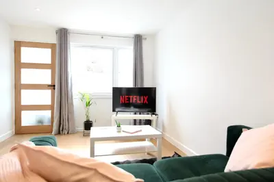 a living room with a green couch and a tv at Stylish Cambridge City Pad in Chesterton