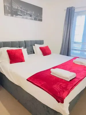 a bedroom with a large bed with red sheets and pillows at Starview Apartment 101 in Colchester