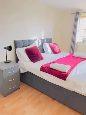 a large bed with red and white pillows on it at Starview Apartment 101 in Colchester
