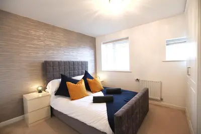 a bedroom with a bed with orange and blue pillows at Large Stylish Cambridge House (4BR/Free Parking) in Cambridge