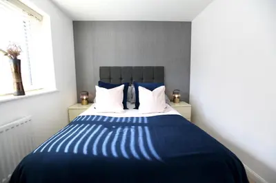 a blue and white bed in a room with a window at Large Stylish Cambridge House (4BR/Free Parking) in Cambridge