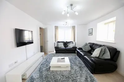 a living room with a black leather couch and a tv at Large Stylish Cambridge House (4BR/Free Parking) in Cambridge