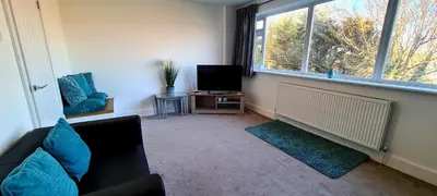 a living room with a couch and a tv and a window at Station Heights in Rayleigh