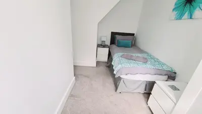 a small bedroom with a bed in a white room at Station Heights in Rayleigh
