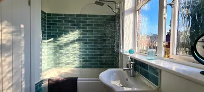 a bathroom with a sink and a green tiled wall at Station Heights in Rayleigh