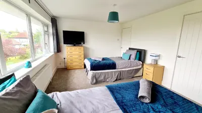 a bedroom with two beds and a tv and a couch at Station Heights in Rayleigh