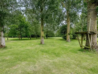 a park with trees and a wooden stand in the grass at Coach House - Uk33307 in Mellis