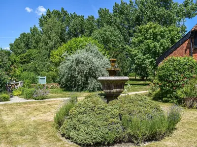 a garden with a large vase in the grass at Coach House - Uk33307 in Mellis