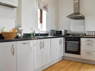 a kitchen with white cabinets and black counter tops at Fallow Cottage - Uk33488 in Hadleigh
