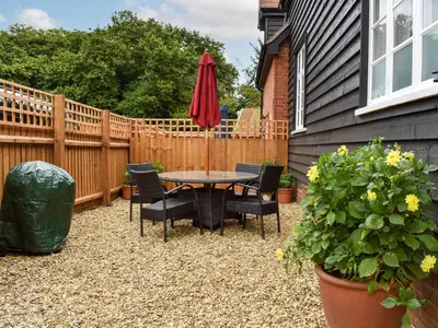 a patio with a table and chairs and an umbrella at Fallow Cottage - Uk33488 in Hadleigh