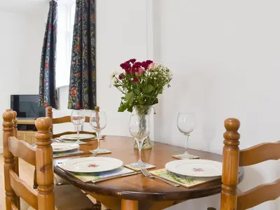 a dining room table with glasses and a vase of flowers at Roe Cottage - Uk33490 in Hadleigh