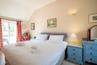 a bedroom with a large white bed with a blue dresser at The Stables, Theberton in Theberton