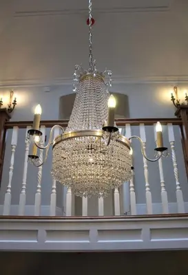 a chandelier with candles is hanging from a staircase at Reymerston Hall in Norwich