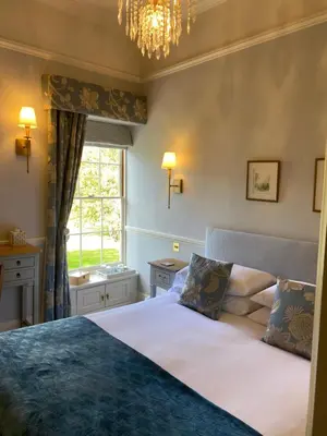 a bedroom with a bed and a window and a chandelier at Reymerston Hall in Norwich