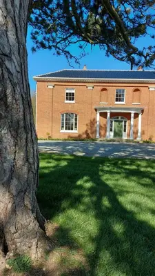 a large brick building with a tree in front of it at Reymerston Hall in Norwich