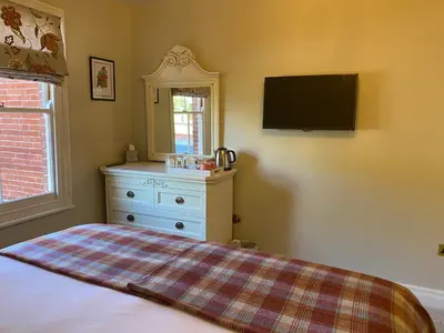 a bedroom with a dresser and a tv on the wall at Reymerston Hall in Norwich