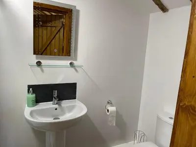 a white bathroom with a sink and a mirror at The Cow Shed - Sleeps 4 Parking & Pet Friendly in Bradwell on Sea