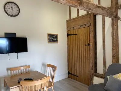 a living room with a table and a wooden door at The Cow Shed - Sleeps 4 Parking & Pet Friendly in Bradwell on Sea