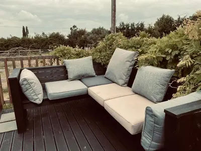 a wooden bench with pillows on a deck at Alfie Acres - Secluded Cabin set in 5 Acres of Privacy, with Exclusive use of Swimming Pool and Hot Tub for up to 10 Guests in Downham