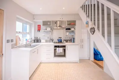 a white kitchen with a sink and a staircase at 6 West Lane in Aldeburgh - Beautiful cottage near high street in Aldeburgh