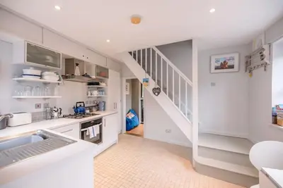 a kitchen with white cabinets and a stairway at 6 West Lane in Aldeburgh - Beautiful cottage near high street in Aldeburgh