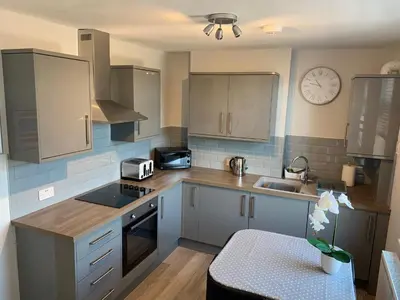 a kitchen with gray cabinets and a clock on the wall at Eclipse Apartment No 4 in Newmarket