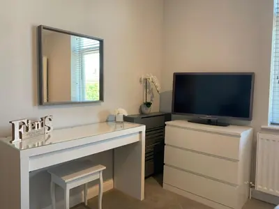 a living room with a tv and a dresser with a mirror at Eclipse Apartment No 4 in Newmarket