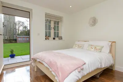 a white bedroom with a bed and a large window at Breckland Cottage - Secluded Country Getaway in Hockwold cum Wilton