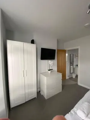 a bedroom with a white cabinet and a television at Eclipse Apartment No 3 in Newmarket