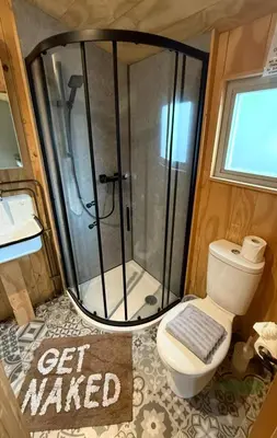 a bathroom with a shower with a toilet and a sign at Keepers Cottage in Ipswich
