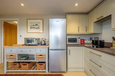 a kitchen with a stainless steel refrigerator at White Cottage Apartment in Snape