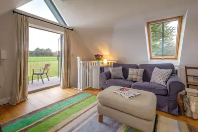 a living room with a purple couch and a window at White Cottage Apartment in Snape