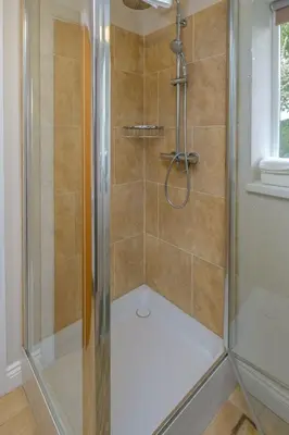 a shower with a glass door in a bathroom at White Cottage Apartment in Snape