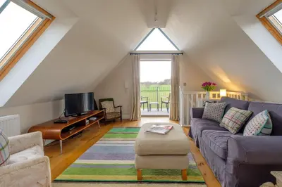 a living room with a couch and a piano at White Cottage Apartment in Snape