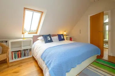 a bedroom with a bed and a book shelf at White Cottage Apartment in Snape