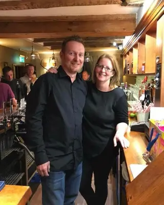a man and a woman standing next to a bar at The Swan Inn in Monks Eleigh