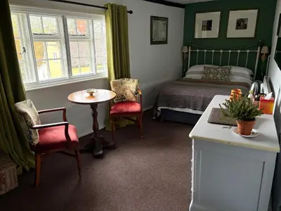 a bedroom with a bed and a table and chairs at The Swan Inn in Monks Eleigh