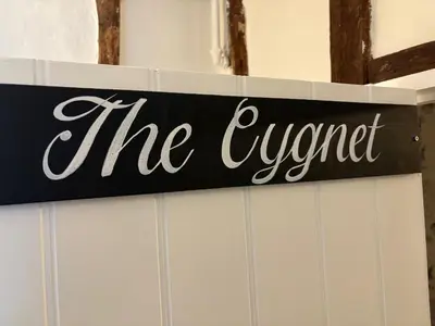 a sign that says the owner on a wall at The Swan Inn in Monks Eleigh