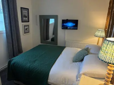 a bedroom with a bed and a tv on the wall at The Swan Inn in Monks Eleigh