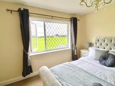a bedroom with a bed and a large window at Cosy Cottage Great Bentley near station and shops in Great Bentley