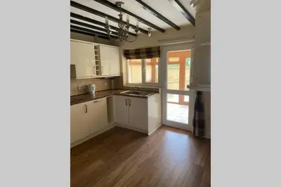 a kitchen with white cabinets and a wooden floor at Cosy Cottage Great Bentley near station and shops in Great Bentley