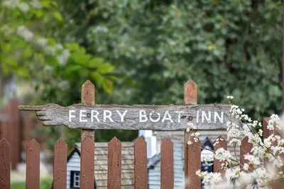 a wooden sign on the top of a fence at The Ferry Boat Inn in North Fambridge