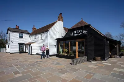 a man standing in front of a white building at The Ferry Boat Inn in North Fambridge