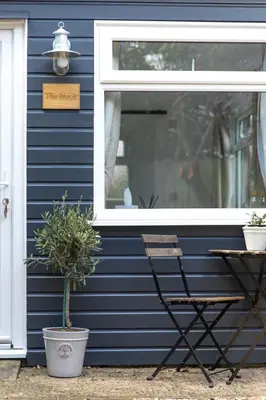 a sign on a blue house with a chair and a window at The Nook in West Mersea