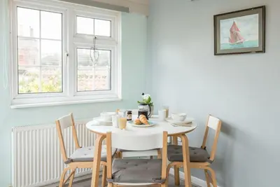a white dining room with a white table and chairs at Suncatch Corner, Saxmundham in Saxmundham