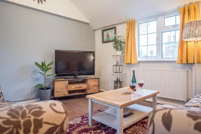 a living room with a flat screen tv and a table at Suncatch Corner, Saxmundham in Saxmundham
