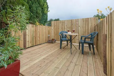 a patio with two chairs and a table in front of a fence at Suncatch Corner, Saxmundham in Saxmundham